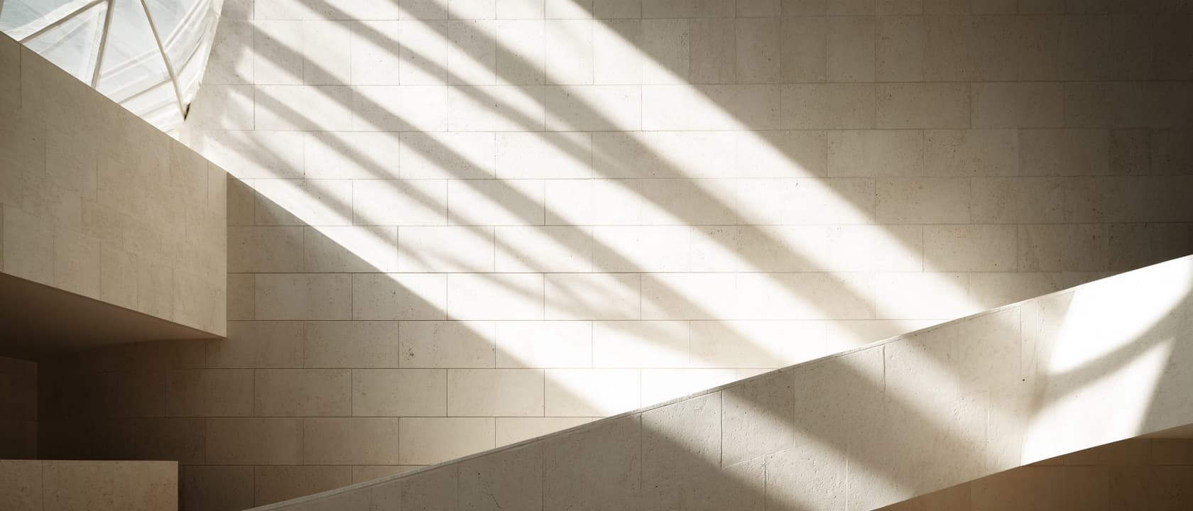 Daylight crossing the limestone walls and walkways of an atrium